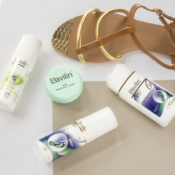 A gold sandal, Lavilin's foot deodorant cream, foot moisturizing gel, foot repair emulsion, and fragrance free foot deodorant products on a white and beige background.